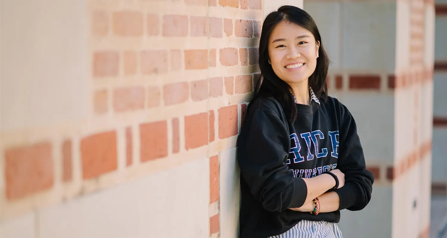 Student standing against wall of McNair Hall
