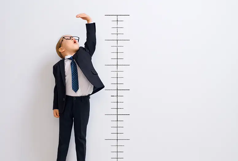 Child wearing a suite being measured.